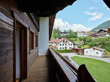WIr stehen auf dem Balkon und sehen die Lichtbeflutetetn Berge und Wiesen