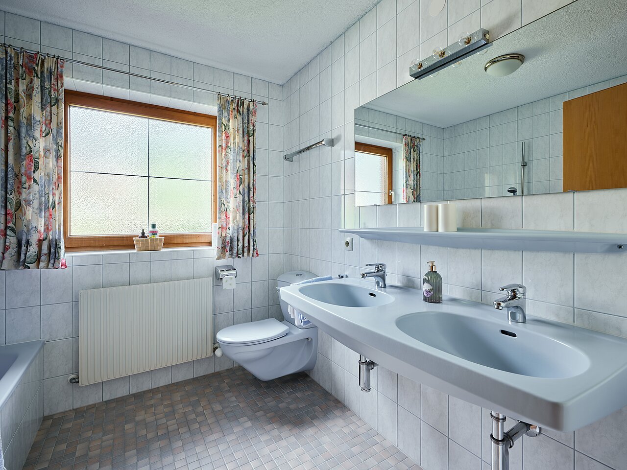 Blick in das helle Badezimmer mit Waschbecken, Dusche und WC