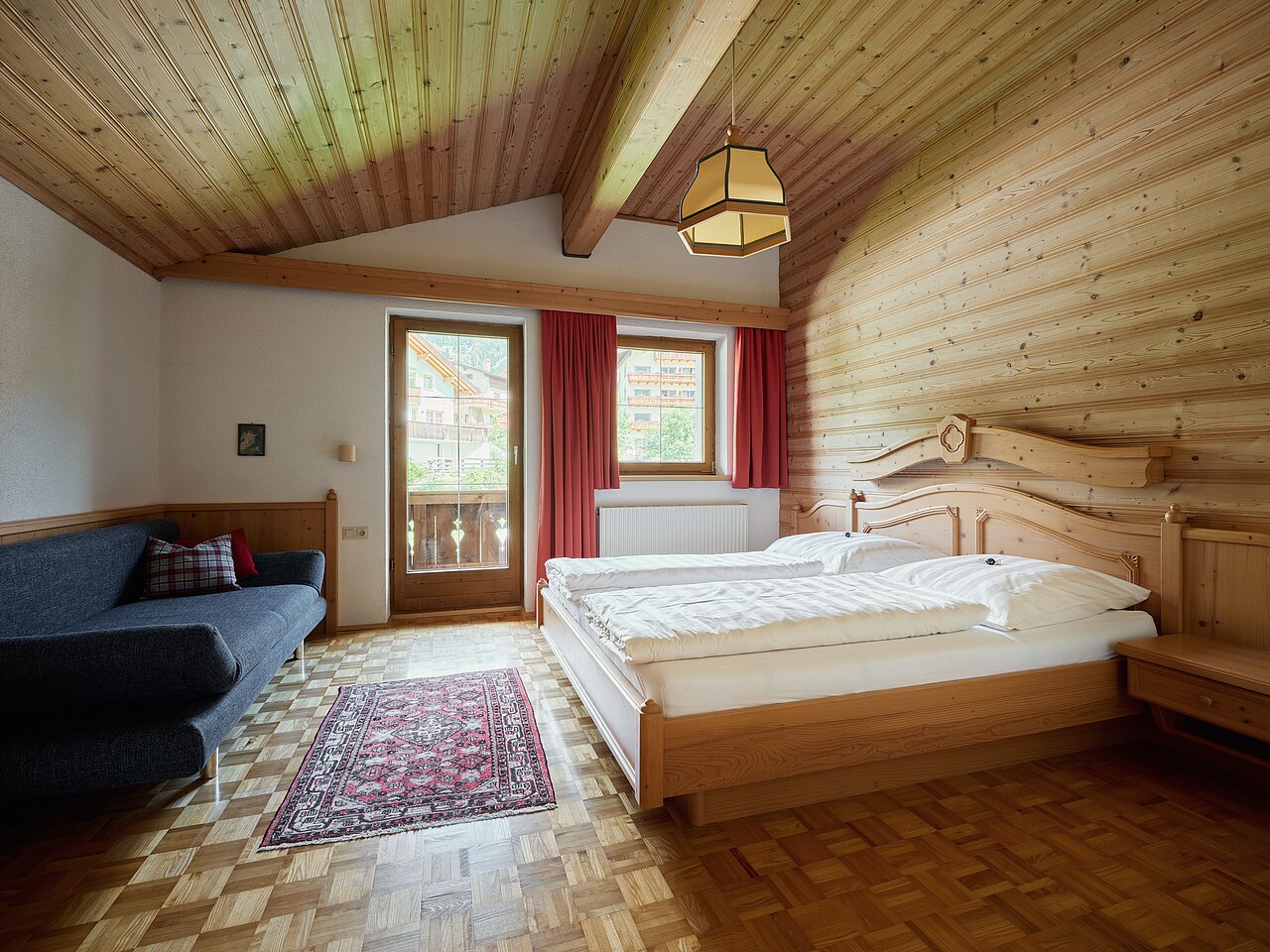 Überblick über das Schlafzimmer mit Doppelbett und kleinem Sofa